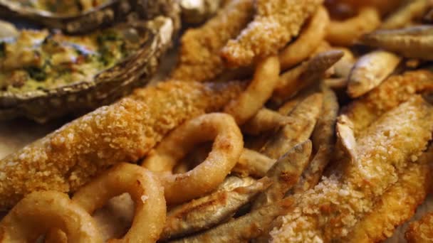 Se sirve pescado frito mezclar la composición de los alimentos. Cocinero hizo anillos de calamar, espadín, gobies, ostras en una bandeja en un restaurante asiático de lujo. Deliciosos aperitivos y salsas en la cafetería. — Vídeo de stock