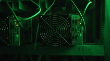 Bitcoin madencileri büyük çiftlikte. Kürsüdeki ASIC madencilik ekipmanları çelik konteynırdaki kripto para birimini rafa kaldırıyor. Engelleme teknolojisi. Güç kaynağı vantilatörleri ve ızgaralar. Sunucu odası yanıp sönen ışıklar.