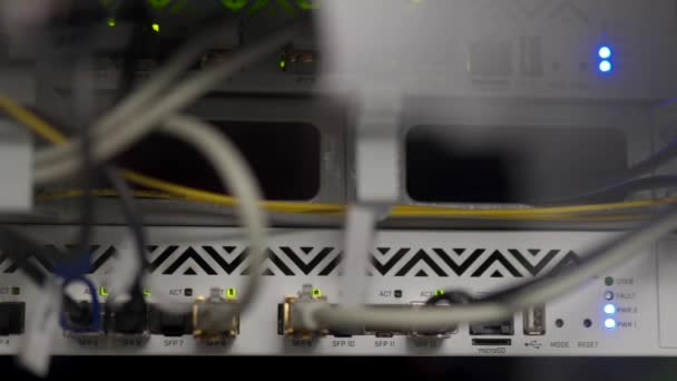 Optischer Server und Router im Serverraum des Rechenzentrums. Netzwerkgeräte blinken mit Lichtern auf dem Gepäckträger. Glasfaserkabel, die mit Ports verbunden sind. Schnelles Internet. — Stockvideo