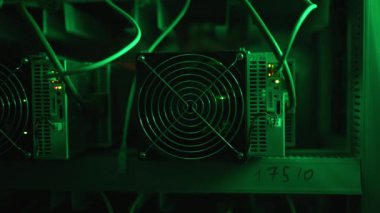 Bitcoin madencileri büyük çiftlikte. Kürsüdeki ASIC madencilik ekipmanları çelik konteynırdaki kripto para birimini rafa kaldırıyor. Engelleme teknolojisi. Güç kaynağı vantilatörleri ve ızgaralar. Sunucu odası yanıp sönen ışıklar.