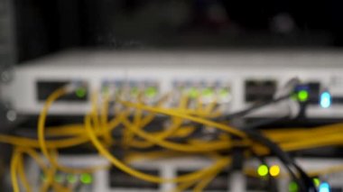 Veri merkezi sunucu odasının optik sunucusu ve yönlendiricisi. Ağ ekipmanları ışıklarla yanıp sönüyor. Optik fiber kablolar bağlantı noktalarına bağlı. Yüksek hızlı İnternet.