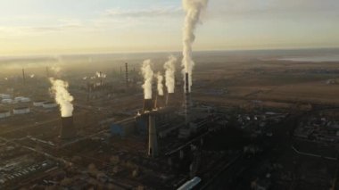 Termik santralin hava görüntüsü. İnsansız hava aracı günbatımında baca dumanı borularının ve sanayi bölgesinin soğutma kulelerinin üzerinden uçuyor. Yukarıdan gelen termal elektrik üretim istasyonu hava emisyonlarını tüketiyor.