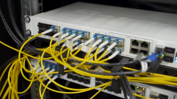 Οπτικός διακομιστής και δρομολογητής του data center server room. Εξοπλισμός δικτύου που αναβοσβήνει με φώτα στη σχάρα. Καλώδια οπτικών ινών συνδεδεμένα με θύρες. Internet υψηλής ταχύτητας. — Αρχείο Βίντεο