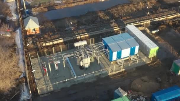 Aerial nad transformatorem elektroenergetycznym z kablami w podstacji rozdzielczej w słoneczny dzień. Aktywny wentylator chłodzący na nowoczesnym transformatorze. Linia wysokiego napięcia na izolatorach. — Wideo stockowe