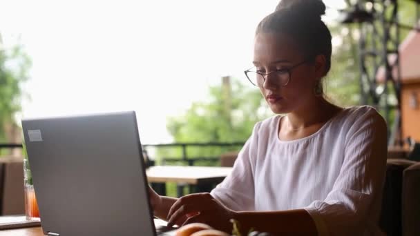 Jeune femme métisse travaillant avec un ordinateur portable dans un café à un endroit tropical. Asiatique caucasienne étudier en utilisant Internet. Femme d'affaires qui fait du marketing social et du shopping. Concept de télétravail . — Video