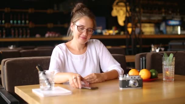 Mujer joven de raza mixta desbloquea su teléfono inteligente con huella digital sentado en la cafetería. Mujer navegando aplicación de red social en su teléfono en coffeshop. Chica descansando en el descanso con un vaso de jugo fresco. — Vídeos de Stock