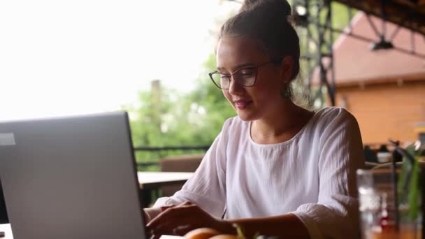 Ung blandet race kvinde arbejder med laptop i cafe på tropisk placering. Asiatisk kaukasiske kvindelige studerer ved hjælp af internettet. Business kvinde gør social markedsføring arbejde og shopping. Telekommunikationskoncept . – Stock-video