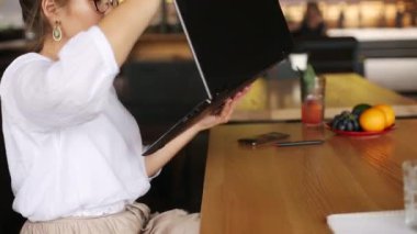 Karışık ırk serbest çalışanı, kafede çalışırken üstü açık dizüstü bilgisayarı tablete dönüştürüyor. Transformatör defterli Asyalı beyaz iş kadını. Dijital sanatçı dokunmatik ekranlı 1 bilgisayarda 2 kullansın.