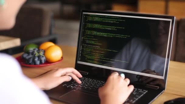 Vue arrière sur la prise de vue épaule du développeur programmeur femelle avec ordinateur portable. Code de programme et données de script à l'écran. Jeune femme pigiste travaillant sur un projet dans un café. — Video