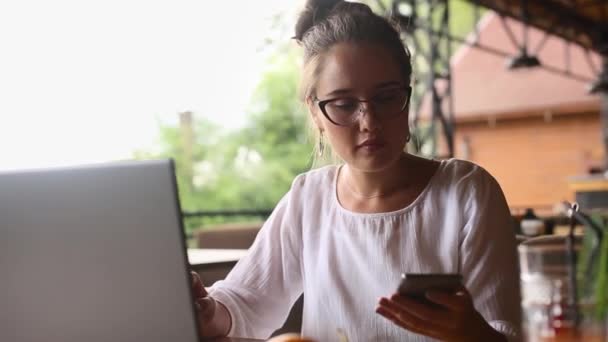 Mixed-Race-Geschäftsfrau durch Anruf von der Arbeit am Laptop abgelenkt. Freiberuflerinnen telefonieren auf dem Handy, während sie bei der Arbeit auf der Notebook-Tastatur SMS schreiben. Multitasking-Konzept. — Stockvideo