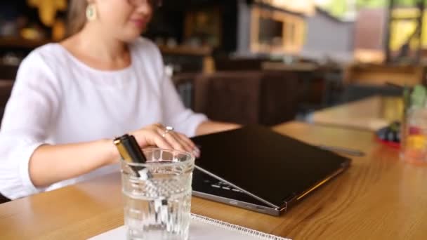 Mujer freelancer abre su computadora portátil, sistema de reconocimiento facial obtiene escaneo de detección facial para acceder a la computadora. La cámara infrarroja escanea la cara femenina. Biometría en electrónica. Mujer comienza a trabajar en la cafetería — Vídeos de Stock