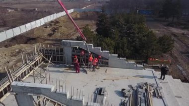 Beton patlayıcı vinç kol kamyonu havadan geliyor. Formalitelere bina karışımı dökülüyor. İnşaat işçileri tribün sahnesinden beton duvarlar dökerler. Yukarıdan görüntüle.
