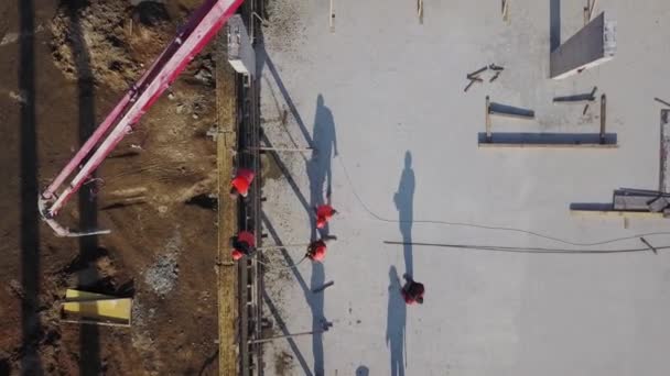 Aerial of concrete boom pump grue arm truck with outriggers couling building mixture into a formwork. Les ouvriers de la construction versent les murs en béton armé de la tribune. Vue d'en haut. — Video