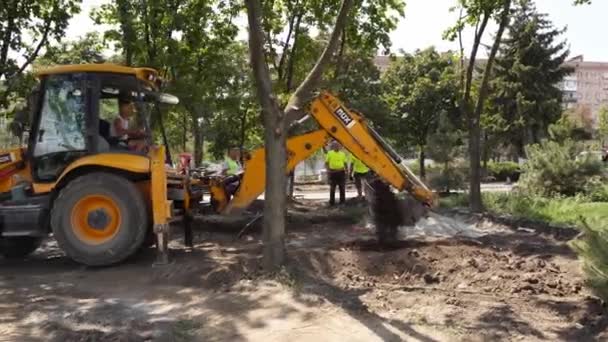 Ukraine, Mariupol - September 1, 2020. Excavator bucket digging ground for construction foundation. TLB doing land surveying work in the city. Heavy equipment for earthwork. — Stock Video