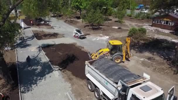 Ukrayna, Mariupol - 1 Eylül 2020. Kazı makinesi inşaat alanında kovayla yer kazıyor. TLB şehir meydanında arazi taraması yapıyor. Toprak işi için ağır ekipman. — Stok video