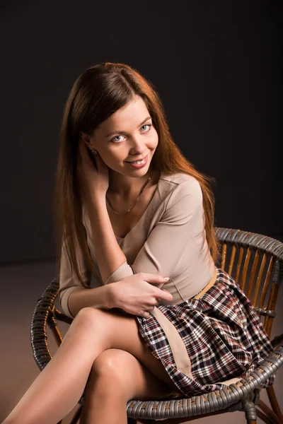 Retrato de una joven atractiva mirándote sentada en una silla — Foto de Stock