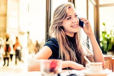 Kafede cep telefonu kullanan kadın