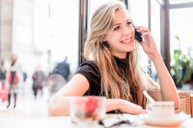 Kafede cep telefonu kullanan kadın