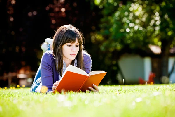 Ung kvinne som leser en bok – stockfoto