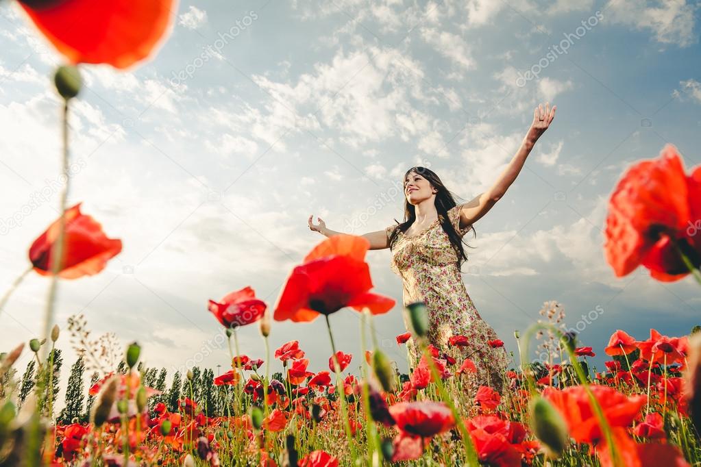 Woman in poppy field at sunset