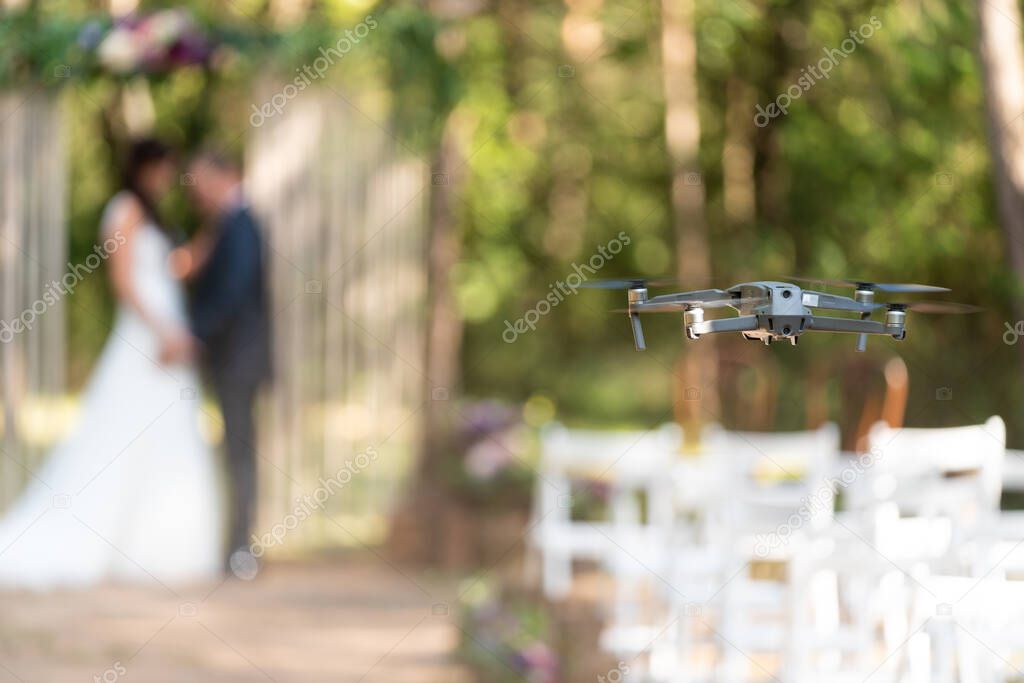 Small gray drone filming and photographing a wedding