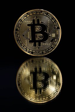 Aynanın tepesinde ve siyah arkaplanda altın bitcoin