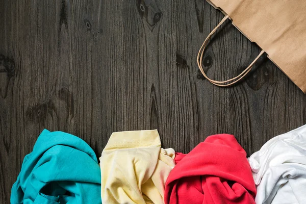 Messy folded clothes and a paper bag — Stock Photo, Image