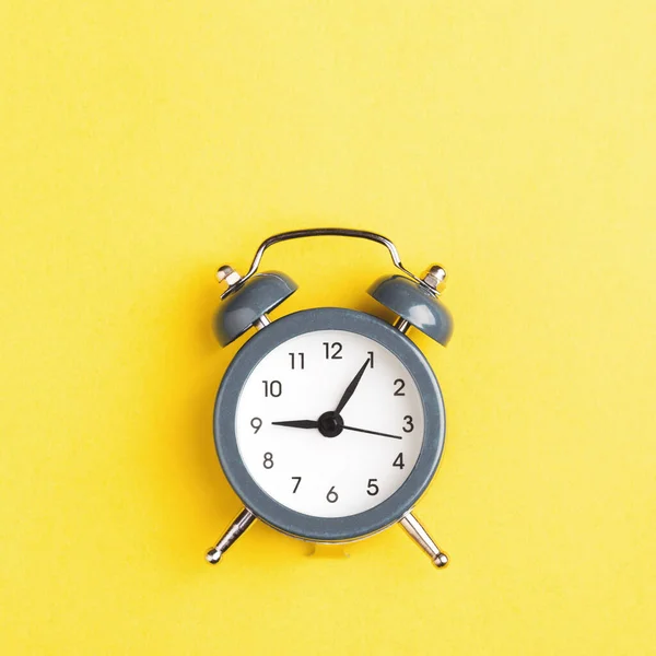 Reloj despertador gris sobre fondo amarillo. — Foto de Stock