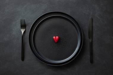 Siyah tabak ve siyah çatal bıçak takımı ve kalp..