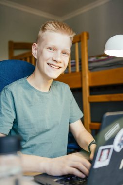 Genç adam gülümsüyor ve kameraya bakıyor..