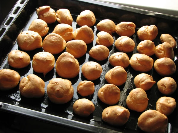 Freshly baked profiteroles on the baking sheet — Stock Photo, Image