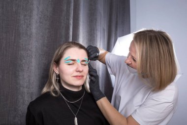 Güzellik salonunda kaş şekillendirmek için mavi balmumu kullanan bir kadın yüzü. Kadınlar için kozmetoloji hizmetleri kavramının aydınlatılması.