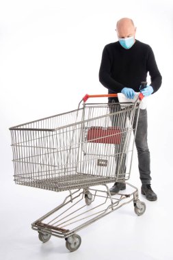 Ağız koruyucusu ve el eldivenli bir adam beyaz arka planda izole edilmiş bir alışveriş arabasını temizliyor.