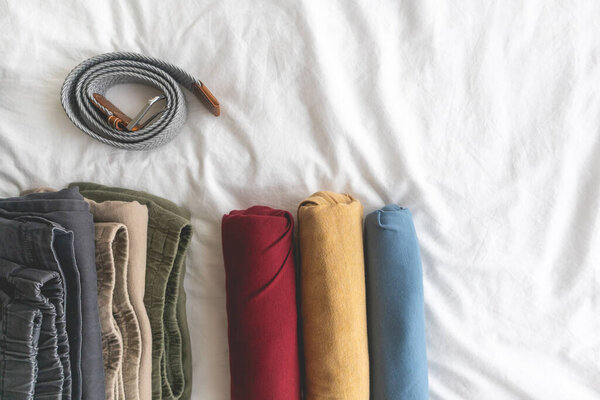 Colorful rolls of t-shirt on the white bed.