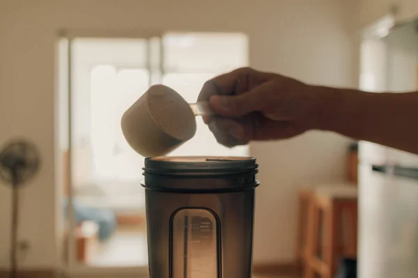 Uomo mettere proteine del siero di latte in polvere nello shaker. — Foto Stock