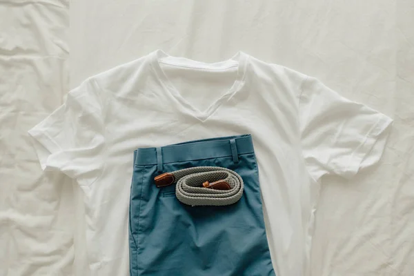 Упаковка одежды на кровати с белой футболкой голубой короткой и одеть пояс. — стоковое фото