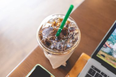 Buzlu kahve dizüstü bilgisayarı ve akıllı telefonu olan bir kafede çalışma alanı.