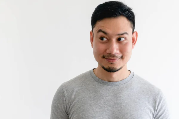 Asiatischer Mann im grauen T-Shirt blickt auf den leeren Raum auf isoliertem E-Hintergrund. — Stockfoto