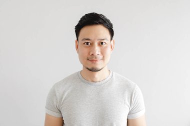 Mutlu bir adamın gülen yüzü gri tişört giyer ve gri arka planda.