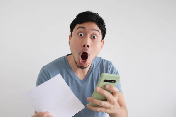 Man is shocked by the bill and the smartphone on isolated background. — Stock Photo, Image