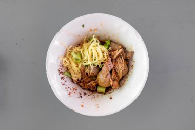 Tayland baharatlı kuru yumurtalı erişte ve küçük kasede servis edilen domuz eti..