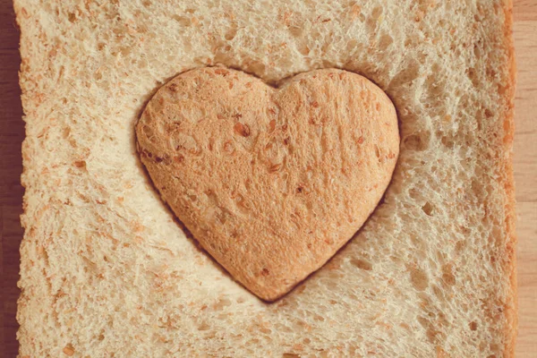 パンはハート型に切り取られます。バレンタインデーの愛とケアの概念. — ストック写真