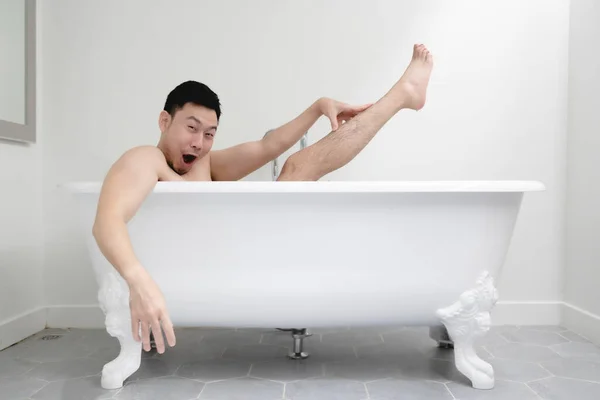 Homem engraçado tentando ser sexy na banheira branca. Conceito de diversão e relaxamento. — Fotografia de Stock