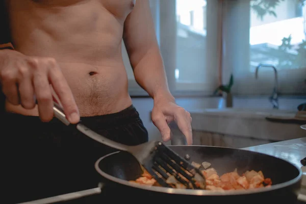 Hombre en topless está cocinando su cena en la cocina. — Foto de Stock