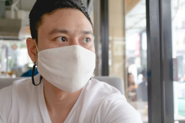 Man wears white mask for Covid virus protection in public cafe.