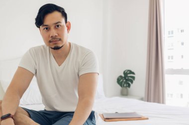 Adam yatak odasında dizüstü bilgisayarla oturuyor..