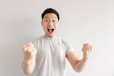 Adam heyecanlanıyor. Adam gri arka planda gri tişört giyiyor..