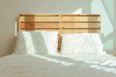 Tavan arası beyaz yatak odası, yumuşak güneş ışığı, kış sabahı..