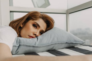 Beyaz tişörtlü, kot pantolonlu bir kadın dairesinde rahatlıyor..