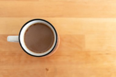 Masanın üstündeki beyaz fincan sıcak kahvenin üst görüntüsü..